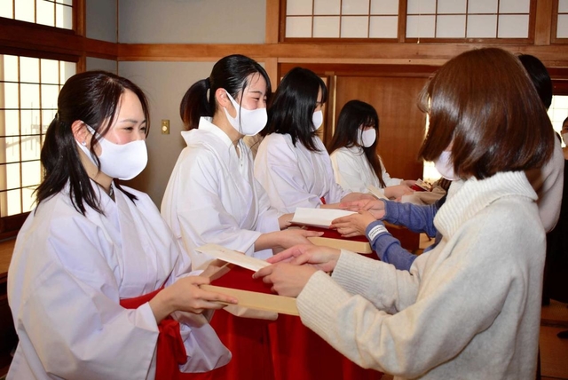 木の皿「折敷」に縁起物を載せて授与の練習をする巫女姿の学生ら＝明石市材木町