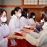 木の皿「折敷」に縁起物を載せて授与の練習をする巫女姿の学生ら＝明石市材木町