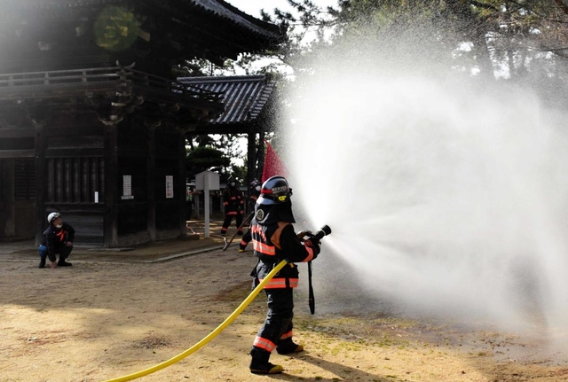 市指定文化財の住吉神社楼門のそばで放水する消防隊員＝明石市魚住町中尾
