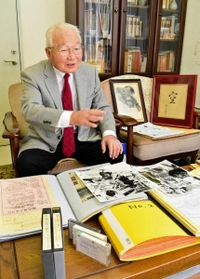 原人まつりの資料を手に思い出を振り返る山根金造さん＝明石市