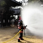 市指定文化財の住吉神社楼門のそばで放水する消防隊員＝明石市魚住町中尾
