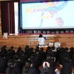 児童らが熱心に聞き入った、絵本の読み聞かせ。壇上には高橋さんの写真も飾られた＝明石市大久保町谷八木