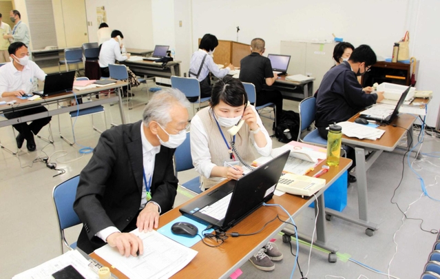電話で聞き取りながらウェブサイトでの予約を代行する市職員＝明石市役所