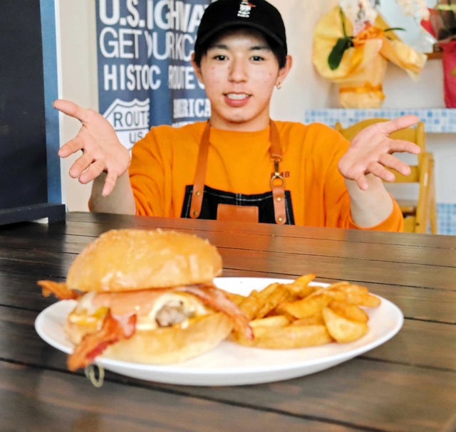 一番人気のベーコンチーズバーガーを前に笑顔を見せる岸本竜生さん＝明石市茶園場町