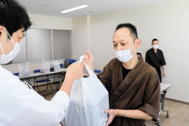 保健所職員に弁当を渡す飲食店主の飯田健二さん＝明石市ゆりのき通１