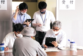 来庁した高齢者の予約手続きをサポートするため、それぞれに端末を操作する市職員＝明石市役所