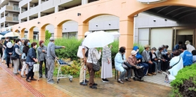 ワクチン接種の予約をするため雨の中、列をつくる高齢者＝明石市大久保町