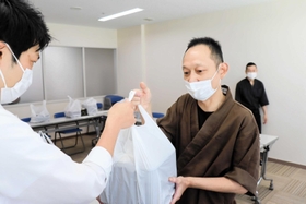 保健所職員に弁当を渡す飲食店主の飯田健二さん＝明石市ゆりのき通１