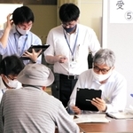 来庁した高齢者の予約手続きをサポートするため、それぞれに端末を操作する市職員＝明石市役所