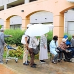 ワクチン接種の予約をするため雨の中、列をつくる高齢者＝明石市大久保町