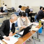 電話で聞き取りながらウェブサイトでの予約を代行する市職員＝明石市役所