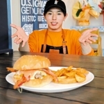一番人気のベーコンチーズバーガーを前に笑顔を見せる岸本竜生さん＝明石市茶園場町