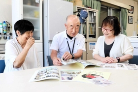 冊子を見ながら３０年を振り返る「和の会」のメンバー＝明石市和坂２