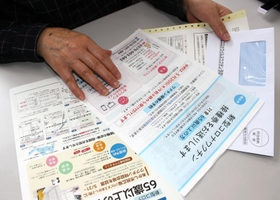 新型コロナウイルスのワクチン接種券を手にする７０代女性。「私は接種しない」＝明石市内