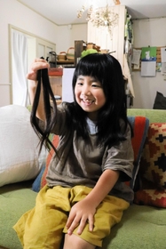 カットした自分の髪を手に持つ有本花糸さん＝明石市