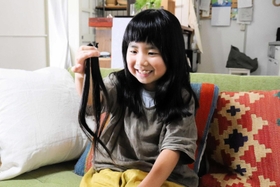 カットした自分の髪を手に持つ有本花糸さん＝明石市