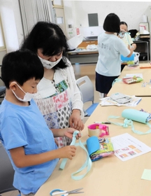お菓子ポシェットづくりに挑戦する児童＝明石市大久保町大久保町