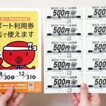 市が全市民に届ける５千円分のサポート利用券（右）と、店舗で掲示されるポスター＝明石市役所