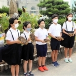 「ひまわりの絆プロジェクト」で育てたヒマワリの種を明石署員に手渡す林小学校の児童会のメンバー＝明石市林崎町１