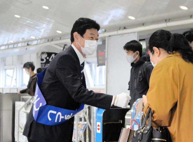 駅構内で支援者らとグータッチを交わす西村氏＝２１日、明石市小久保２