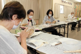 竹籠に和紙を張り付けるお年寄り＝明石市朝霧東町１