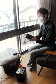 家の窓に設置したソーラーパネルで発電する清水さん＝明石市朝霧台
