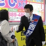 駅構内で支援者らとグータッチを交わす西村氏＝２１日、明石市小久保２