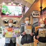 新しく設置されたデジタルサイネージの前でイベントをＰＲする明石銀座商店街の商店主＝明石市桜町