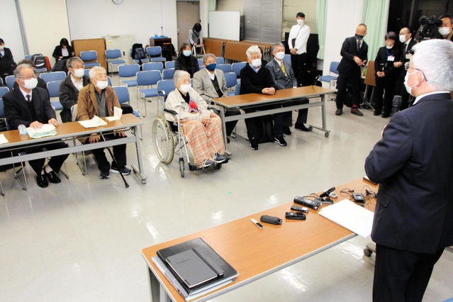 旧優生保護法の被害者支援条例案が可決したことについて、泉房穂市長（右）から報告を受ける小林宝二さん（前列左から２人目）、喜美子さん夫妻＝明石市役所