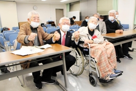 旧優生保護法の被害者支援条例案が可決し、泉房穂市長（中央）と手を握る小林宝二さん（左）、喜美子さん夫妻＝明石市役所