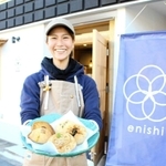 開業したベーカリー＆カフェ「ｅｎｉｓｈｉ」前で総菜パンを手にする塚本ゆかりさん＝明石市大久保町西島