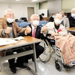 旧優生保護法の被害者支援条例案が可決し、泉房穂市長（中央）と手を握る小林宝二さん（左）、喜美子さん夫妻＝明石市役所