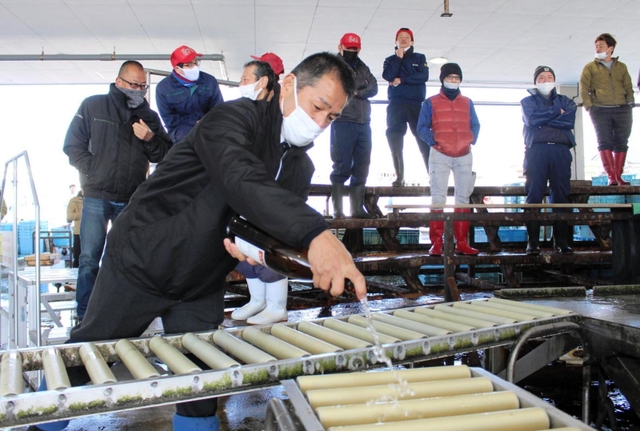 初競り開始直前、魚が運ばれて来るレーンを酒で清める戎本裕明組合長＝明石市岬町