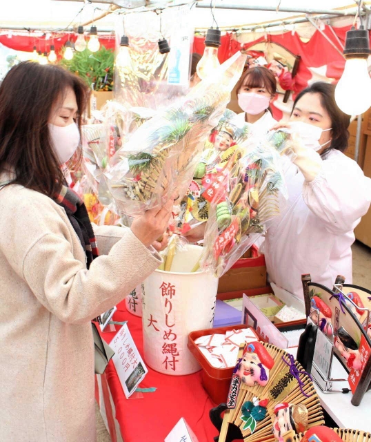 縁起物を買い求める参拝者に笑顔で応対する巫女＝明石市材木町、岩屋神社