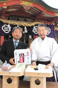 商品サンプルを手にする宮内正次社長（左）と菅谷誠夫宮司＝明石市大蔵本町