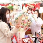 縁起物を買い求める参拝者に笑顔で応対する巫女＝明石市材木町、岩屋神社