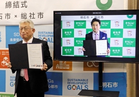 協定書を掲げる泉房穂市長（左）と片岡聡一総社市長＝明石市役所