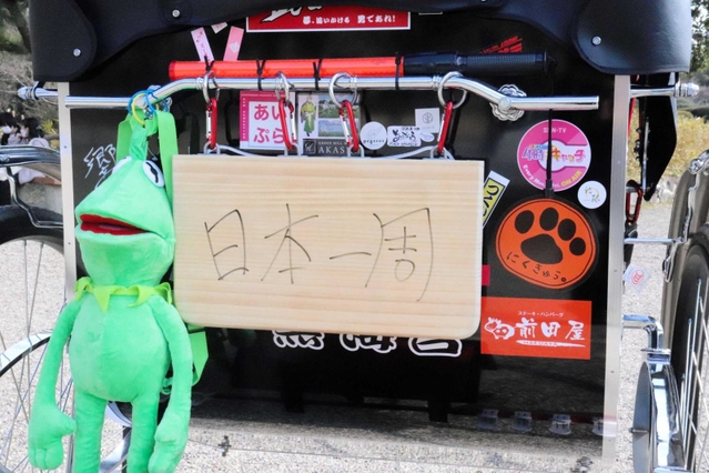 まな板でつくった「日本一周」の看板を掲げて移動する＝明石公園
