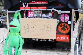 まな板でつくった「日本一周」の看板を掲げて移動する＝明石公園