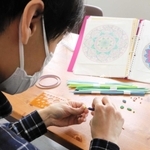 専用の道具を使い、細長く切った色画用紙を巻く永松さん＝明石市相生町１