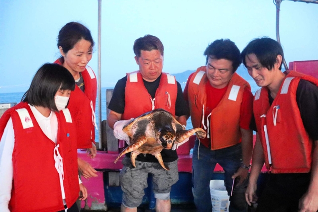 ウミガメを保護した人たち。この後、無事を祈りながら放した＝林崎海岸沖