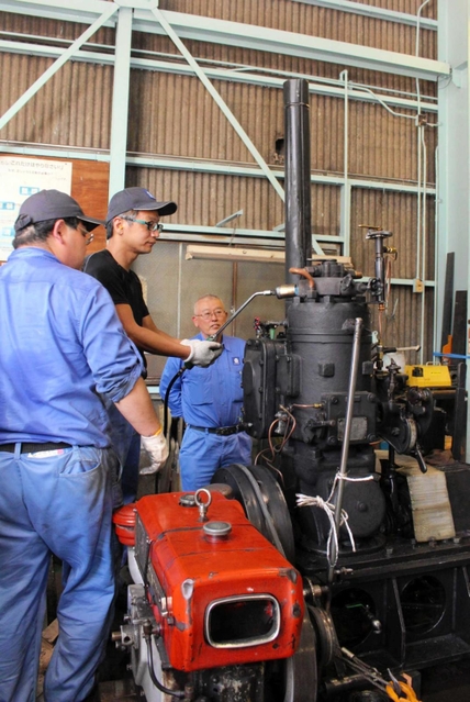 譲り受けた焼玉エンジンを試運転する金井清さん（奥）ら＝明石市港町７、明石発動機工作所