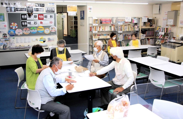 藤江駅前オアシスで打ち合わせする運営ボランティアら＝明石市藤江