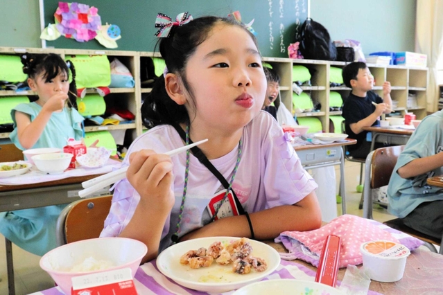 給食のタコの唐揚げを頬張る児童＝明石市二見町東二見