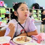 給食のタコの唐揚げを頬張る児童＝明石市二見町東二見