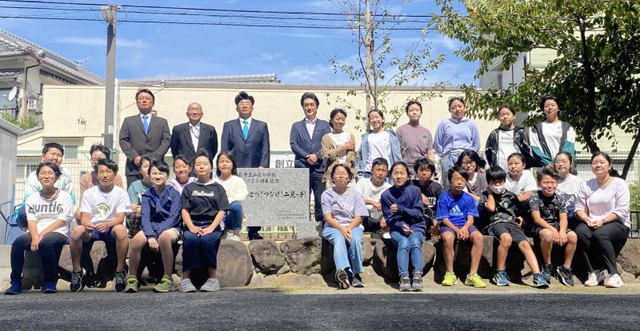 式典後に石碑を囲んで記念撮影する子どもら＝二見小学校