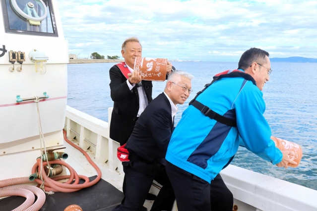 タコつぼを投入する泉房穂明石市長（中央）ら＝二見沖