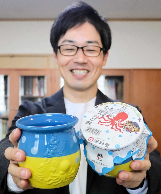 さかなクンとコラボした「ひっぱりだこ飯」を持つ柳本雄基副社長＝神戸市東灘区