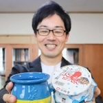 さかなクンとコラボした「ひっぱりだこ飯」を持つ柳本雄基副社長＝神戸市東灘区