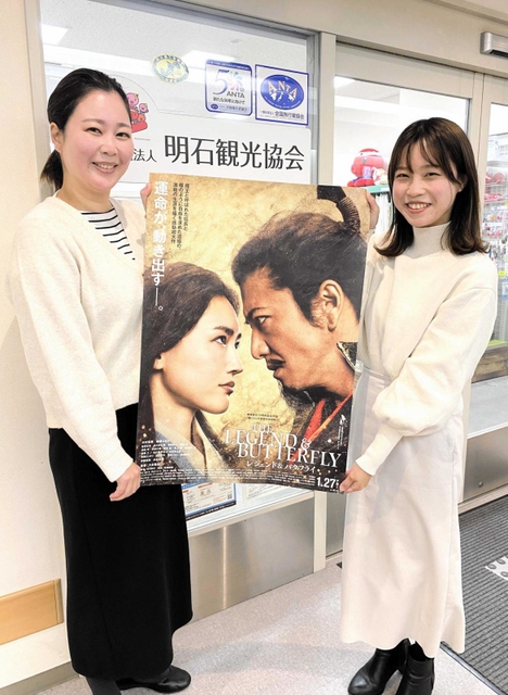 ポスターを手に明石城跡で撮影された映画をＰＲする明石観光協会の前川さん（左）と福田さん＝明石市東仲ノ町